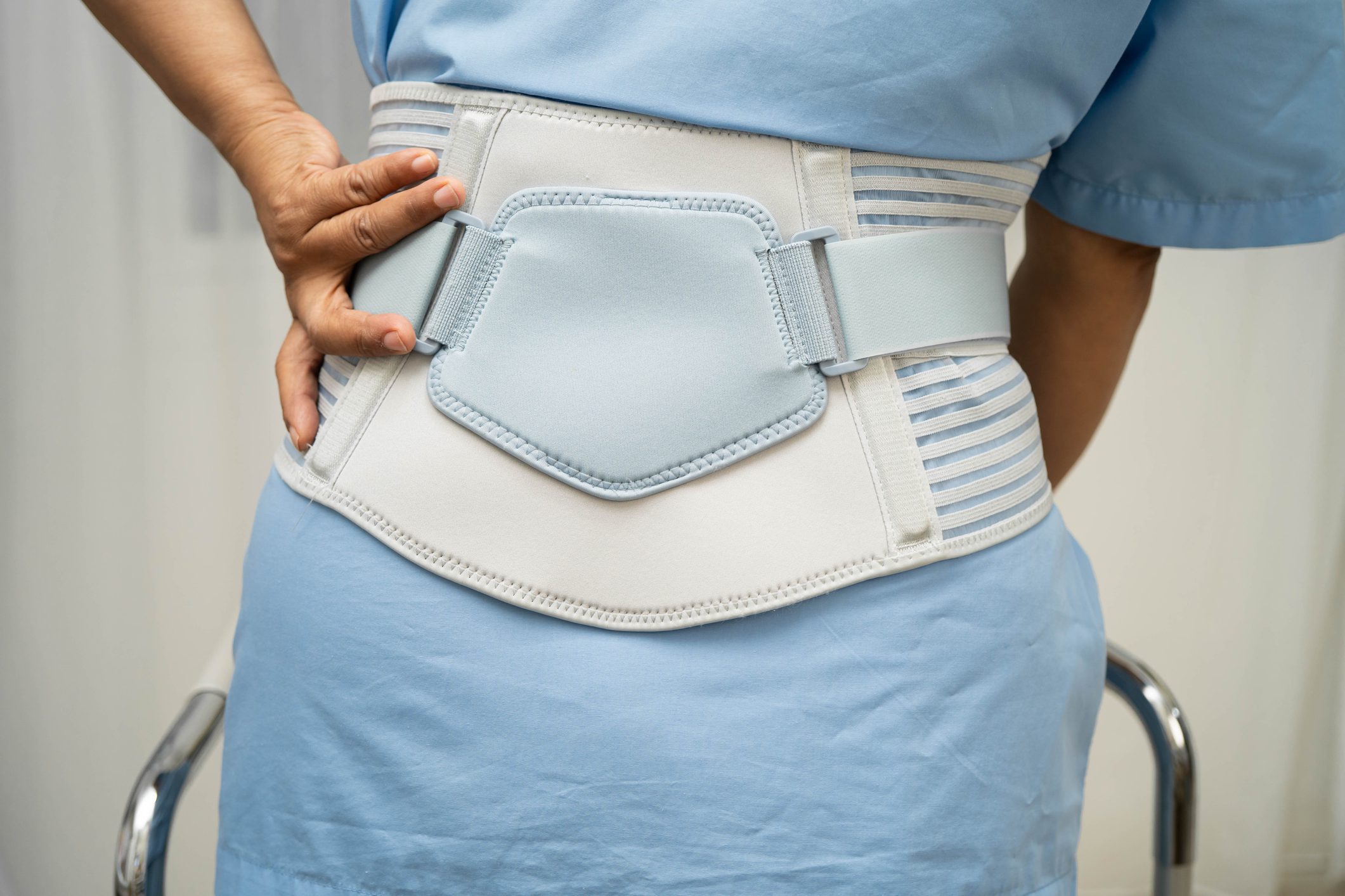 Asian senior pain back wearing elastic support belt with walker.